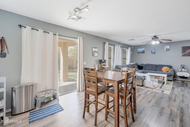 dining space featuring light wood finished floors, plenty of natural light, and visible vents