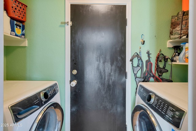 washroom featuring a textured wall, laundry area, and washer and dryer