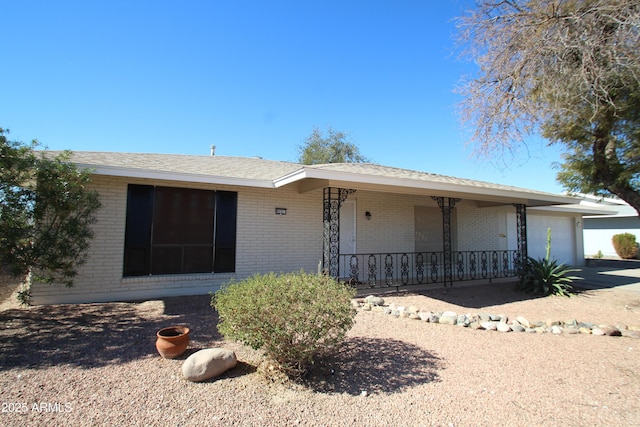 single story home featuring a garage, a porch, concrete driveway, and brick siding