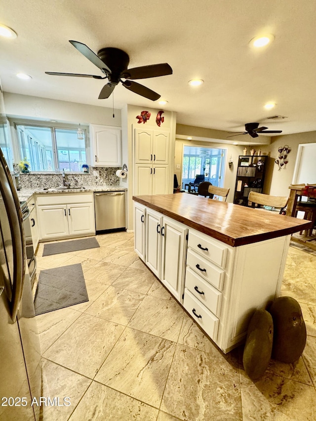 kitchen featuring a sink, butcher block counters, white cabinets, and dishwasher