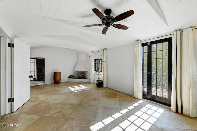 unfurnished living room featuring ceiling fan, a fireplace, and vaulted ceiling