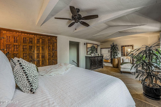 bedroom with lofted ceiling with beams, dark tile patterned floors, and ceiling fan