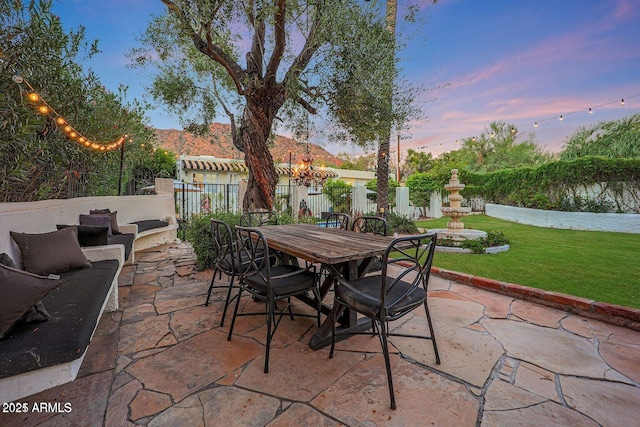 patio terrace at dusk featuring a yard