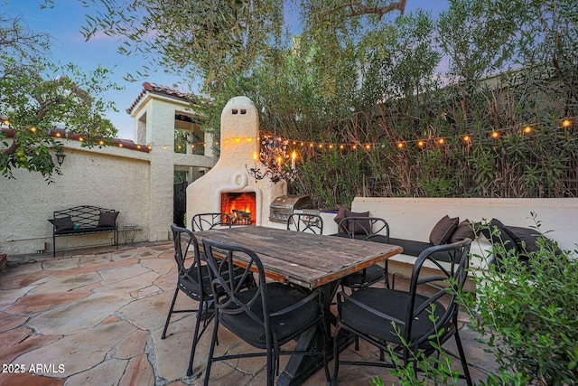 patio terrace at dusk with exterior fireplace