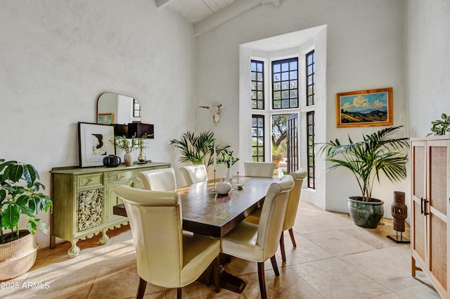 dining room featuring a towering ceiling and light tile patterned floors