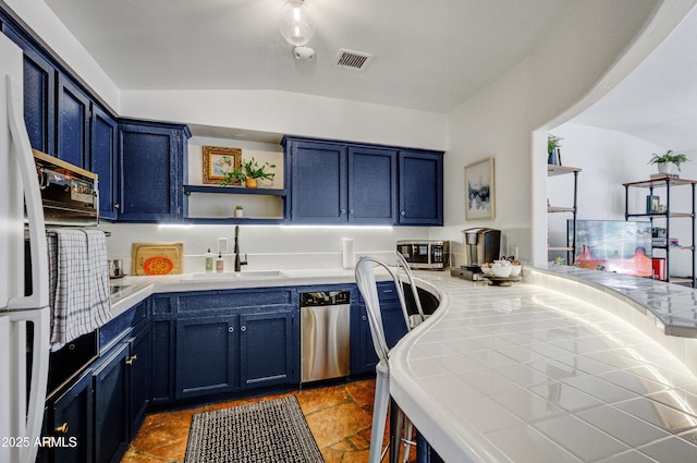 kitchen with blue cabinets, tile countertops, dishwasher, and sink