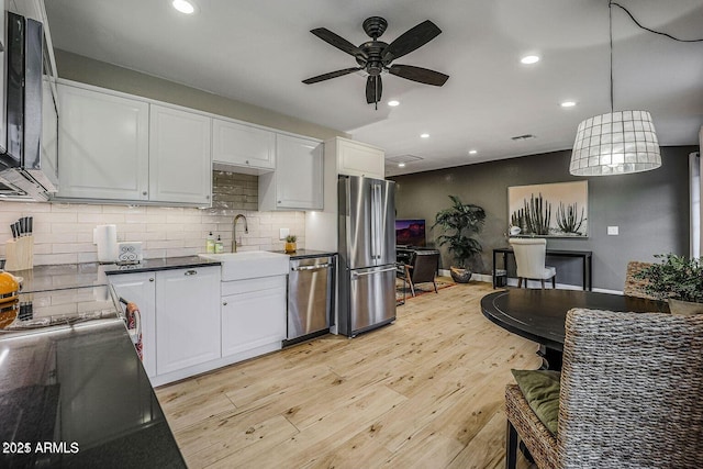 kitchen featuring sink, decorative light fixtures, light wood-type flooring, stainless steel appliances, and white cabinets