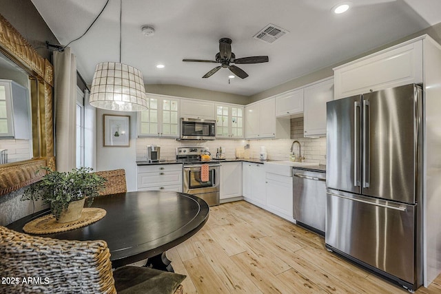 kitchen featuring stainless steel appliances, sink, pendant lighting, and white cabinets