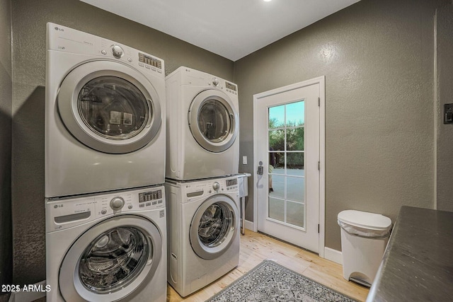 washroom with stacked washer and dryer and light hardwood / wood-style flooring