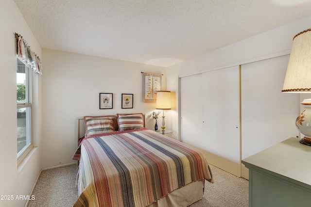 carpeted bedroom with a textured ceiling and a closet