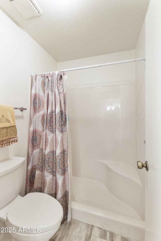 bathroom featuring a shower with curtain, hardwood / wood-style floors, and toilet