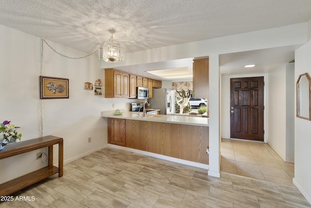 kitchen featuring sink, a notable chandelier, kitchen peninsula, decorative light fixtures, and appliances with stainless steel finishes