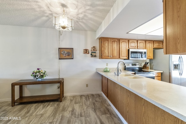 kitchen featuring decorative light fixtures, light wood-type flooring, a textured ceiling, a notable chandelier, and stainless steel appliances