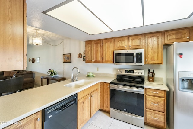 kitchen with appliances with stainless steel finishes, light tile patterned floors, pendant lighting, and sink