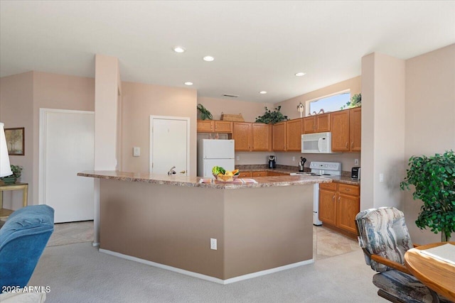 kitchen featuring white appliances, light stone countertops, and a center island with sink