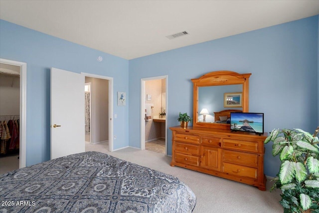 bedroom with connected bathroom, a spacious closet, light colored carpet, and a closet