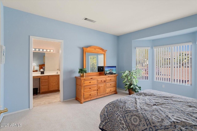 bedroom featuring light colored carpet and ensuite bathroom