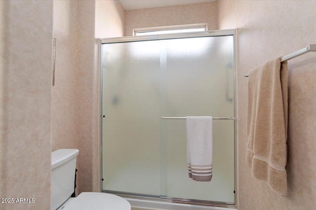 bathroom with a shower with door and toilet