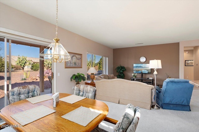 carpeted dining room with an inviting chandelier and plenty of natural light