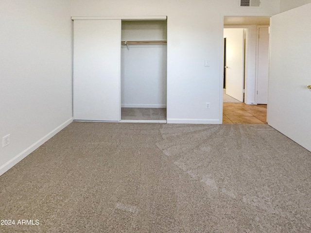 unfurnished bedroom with light carpet and a closet