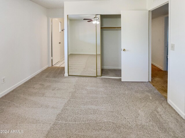 unfurnished bedroom featuring a closet, light colored carpet, and ceiling fan