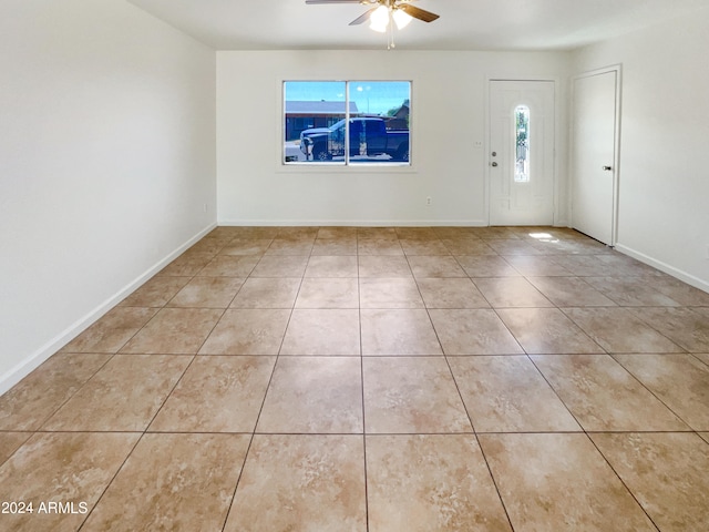 tiled empty room featuring ceiling fan