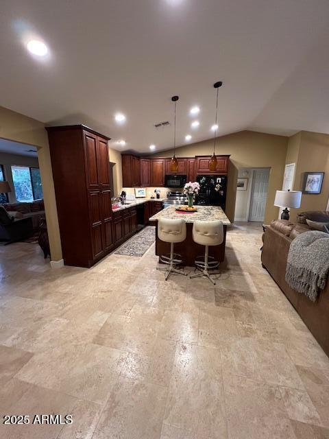 kitchen featuring lofted ceiling, a kitchen bar, a center island, hanging light fixtures, and black appliances