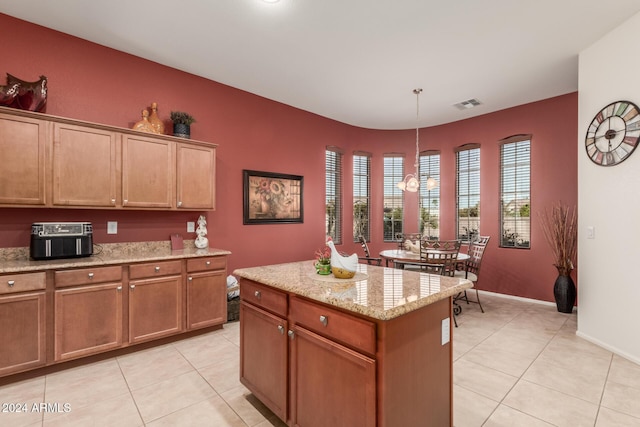 kitchen with decorative light fixtures, a kitchen island, light stone counters, and light tile patterned floors