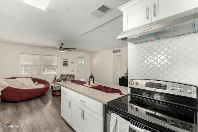 kitchen with ceiling fan, stainless steel electric range oven, light wood-type flooring, white cabinetry, and exhaust hood