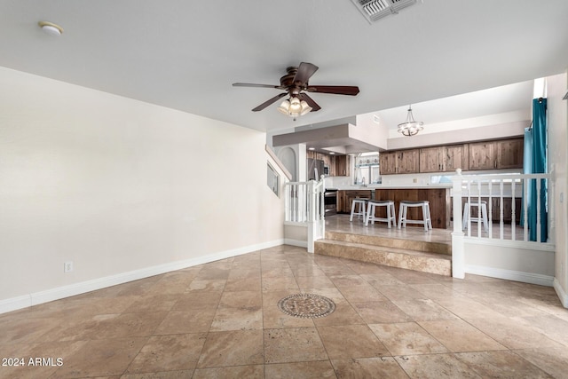 unfurnished living room with ceiling fan with notable chandelier