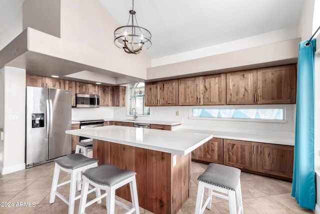 kitchen featuring sink, hanging light fixtures, stainless steel appliances, a chandelier, and a kitchen island