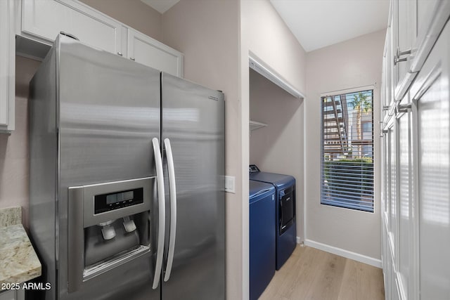 kitchen with stainless steel refrigerator with ice dispenser, white cabinetry, washing machine and clothes dryer, blue cabinetry, and light hardwood / wood-style flooring