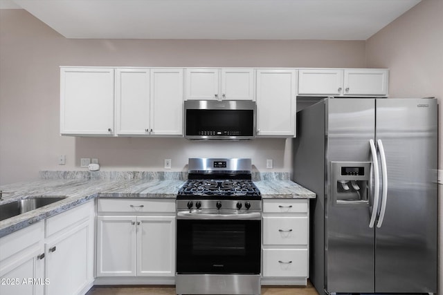 kitchen featuring white cabinets, sink, light stone counters, and stainless steel appliances