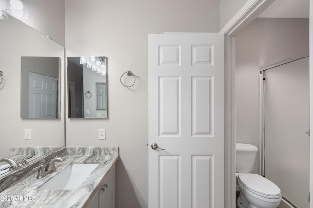 bathroom featuring toilet, vanity, and walk in shower