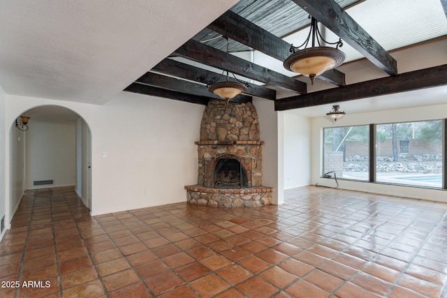 unfurnished living room featuring tile patterned flooring, a textured ceiling, a fireplace, and beam ceiling