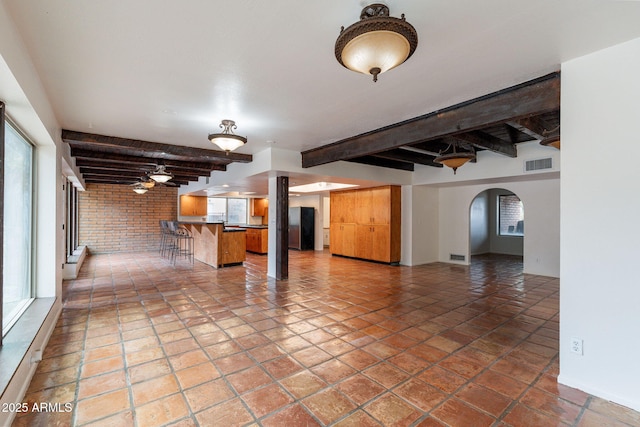 tiled spare room with beamed ceiling and brick wall