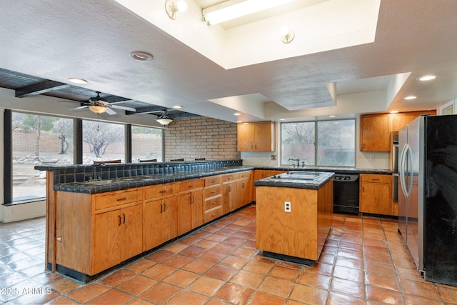 kitchen with a healthy amount of sunlight, stainless steel fridge, a center island, and dishwasher