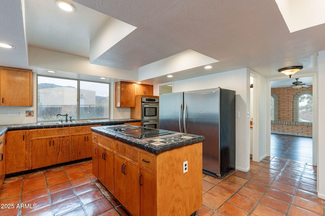 kitchen with appliances with stainless steel finishes, tile countertops, sink, a center island, and light tile patterned floors