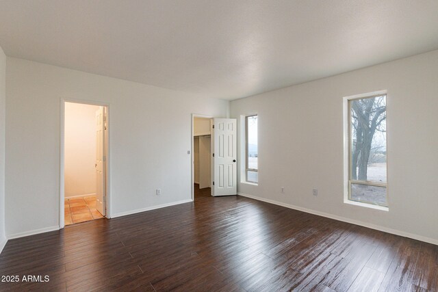 empty room featuring a healthy amount of sunlight and dark hardwood / wood-style floors