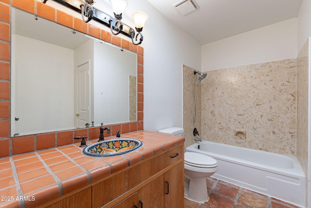 full bathroom featuring tiled shower / bath, vanity, and toilet