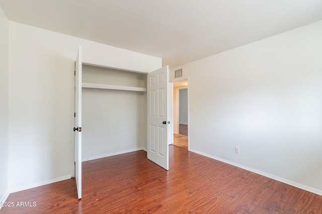 unfurnished bedroom featuring a closet and dark hardwood / wood-style floors