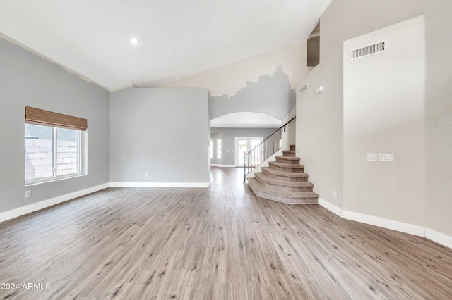 unfurnished living room featuring a towering ceiling and light wood-type flooring