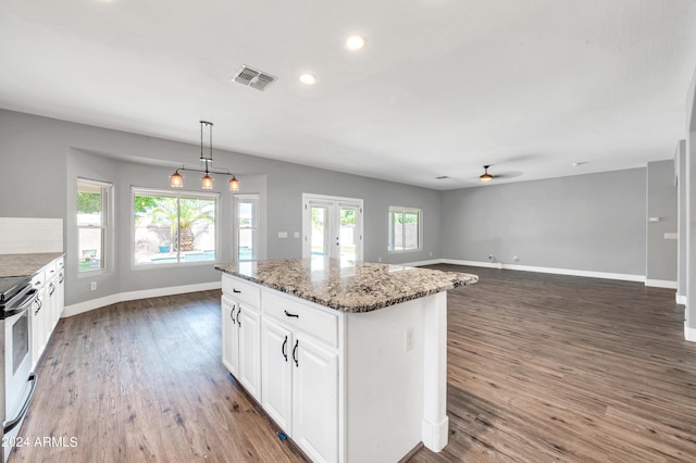 kitchen with white cabinetry, decorative light fixtures, dark hardwood / wood-style flooring, a kitchen island, and dark stone counters