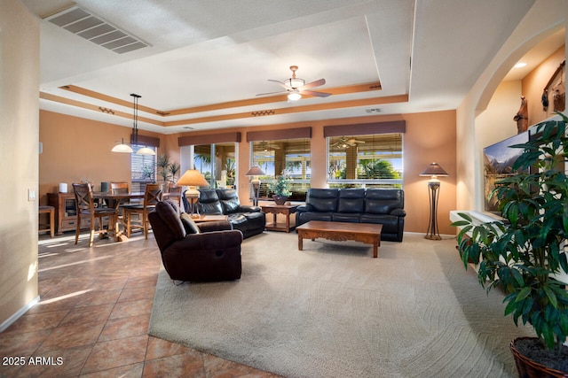 living room with a raised ceiling and ceiling fan