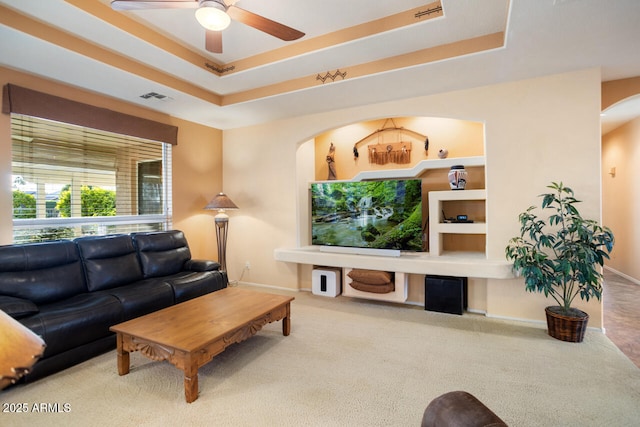 living room featuring ceiling fan, carpet floors, and a tray ceiling