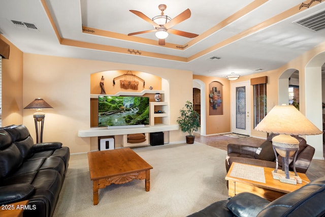 carpeted living room featuring a raised ceiling and ceiling fan