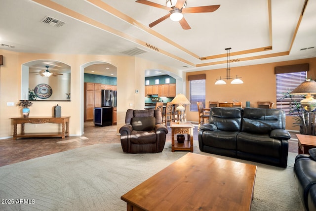 living room featuring ceiling fan and a tray ceiling