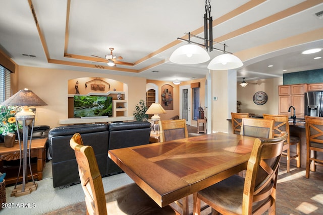 dining area featuring ceiling fan, built in shelves, and a tray ceiling