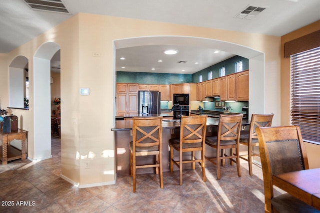 kitchen with sink, a kitchen breakfast bar, and black appliances