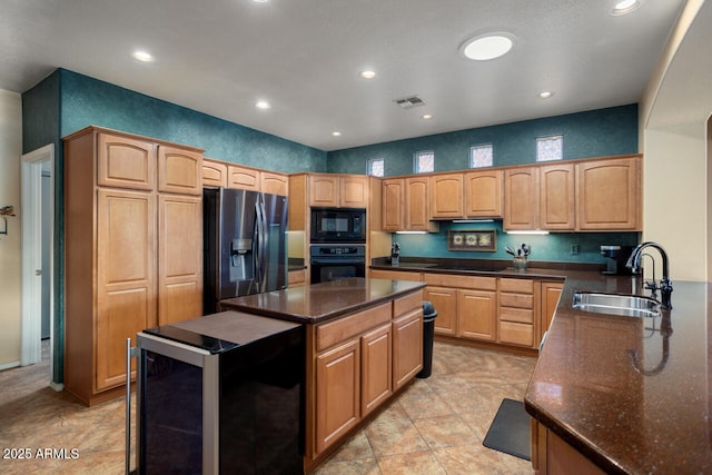 kitchen featuring beverage cooler, dark stone countertops, black appliances, a center island, and sink